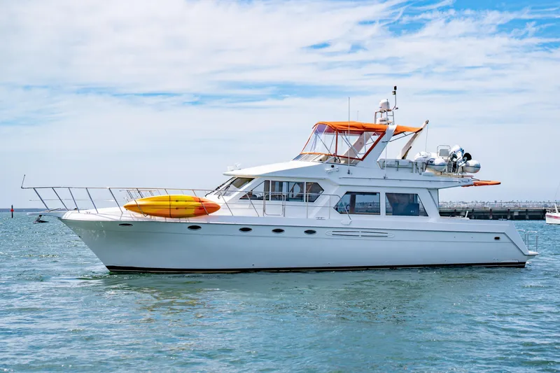 Slide: The Image of Navigator 5300 Classic yacht from 2000 on calm water, featuring a vibrant orange canopy. - 9