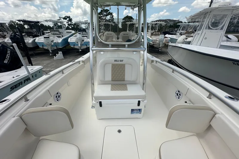 Slide: The Image of 2026 Bulls Bay 255 CC boat interior with seating and console, docked among other boats. - 8