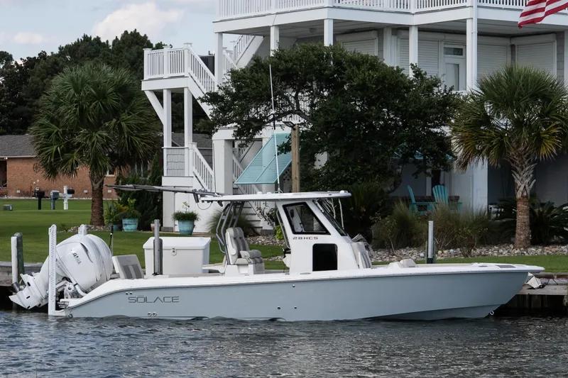 Slide: The Image of 2026 Solace 28 HCS boat docked by a waterfront home with palm trees. - 11