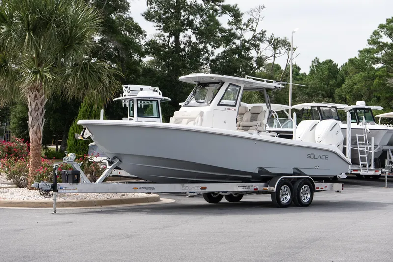 Slide: The Image of 2026 Solace 28 HCS boat on trailer, parked outdoors with trees in background. - 13