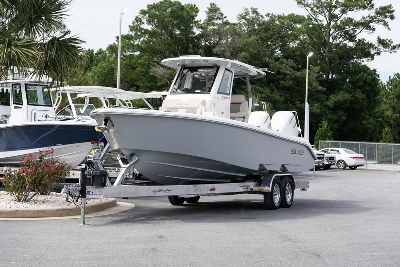 Slide: The Image of 2026 Solace 28 HCS boat on trailer, parked outdoors near other boats. - 14