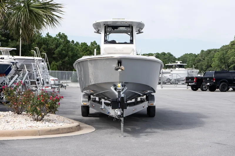 Slide: The Image of 2026 Solace 28 HCS boat on trailer in parking lot, surrounded by trees and other boats. - 15