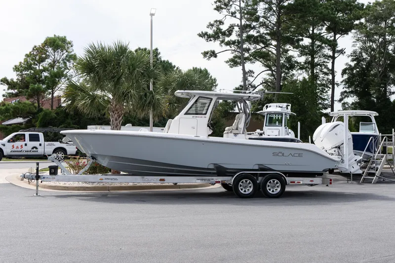 Slide: The Image of 2026 Solace 28 HCS boat on trailer, parked outdoors with trees in background. - 16