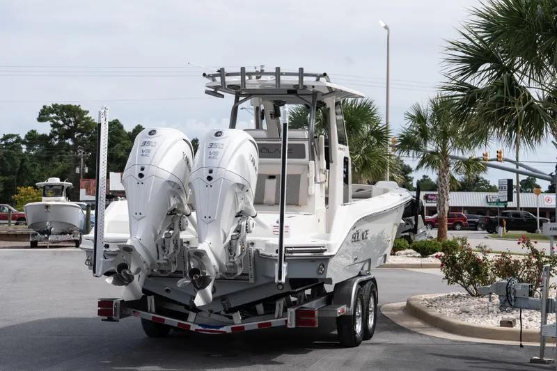 Slide: The Image of 2026 Solace 28 HCS boat on trailer with dual outboard engines, parked near palm trees. - 20