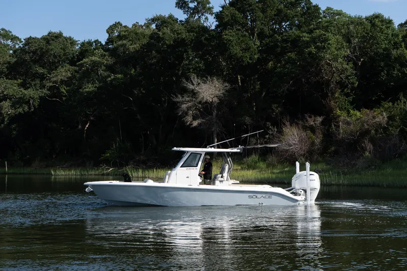 Slide: The Image of 2026 Solace 28 HCS boat cruising on a serene river with lush forest backdrop. - 5