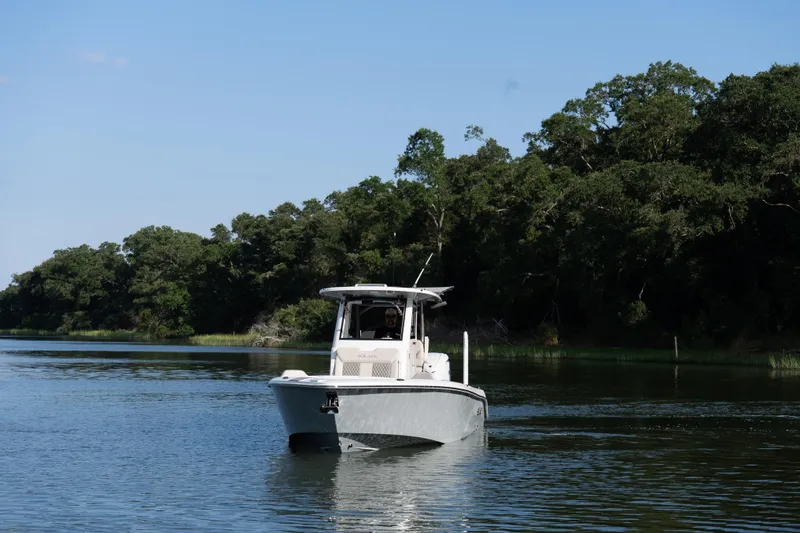 Slide: The Image of 2026 Solace 28 HCS boat cruising on a serene river with lush green trees. - 6