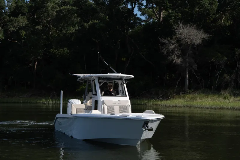 Slide: The Image of 2026 Solace 28 HCS boat cruising on a serene river with lush forest backdrop. - 8