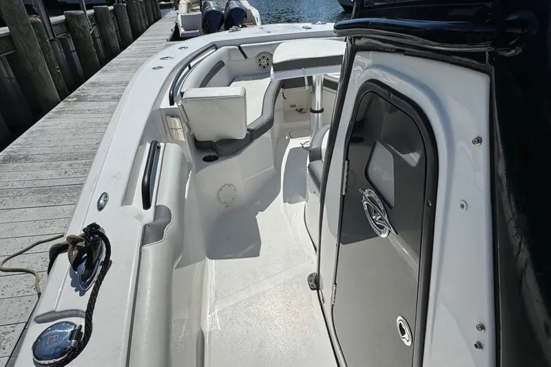 Slide: The Image of 2021 Tidewater 272 CC Adventure boat interior, featuring seating and storage, docked by the water. - 19