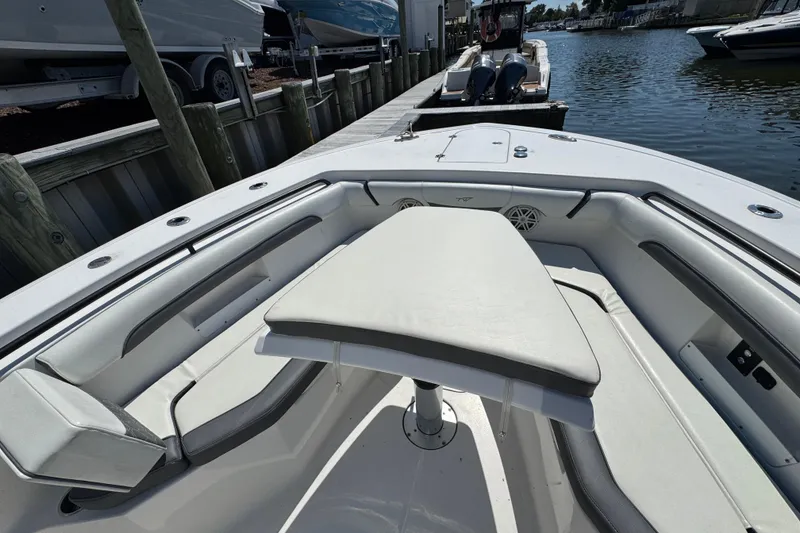 Slide: The Image of 2021 Tidewater 272 CC Adventure boat interior with seating and table, docked by the water. - 22