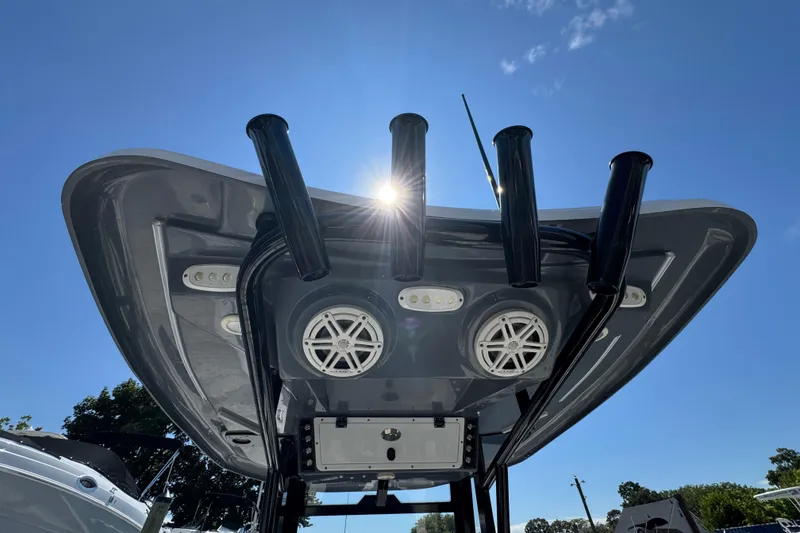 Slide: The Image of 2021 Tidewater 272 CC Adventure boat with rod holders and speakers under a clear sky. - 25