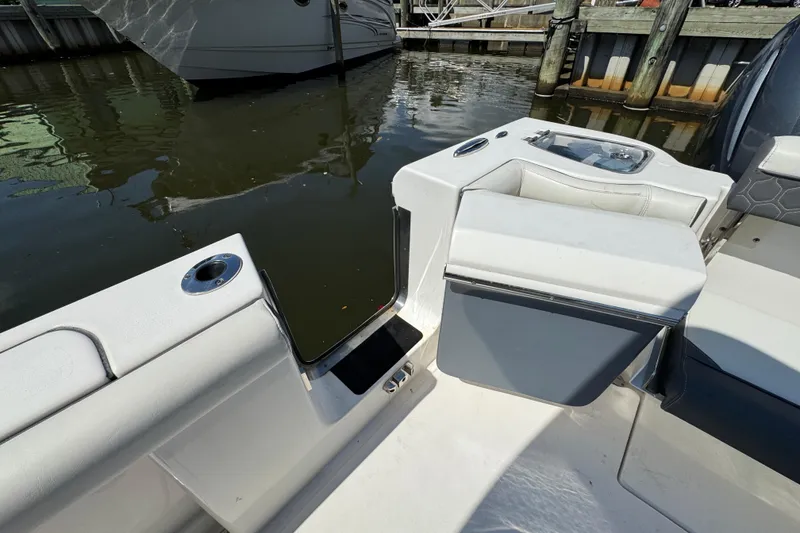 Slide: The Image of 2021 Tidewater 272 CC Adventure boat interior, featuring seating and storage near the water. - 27