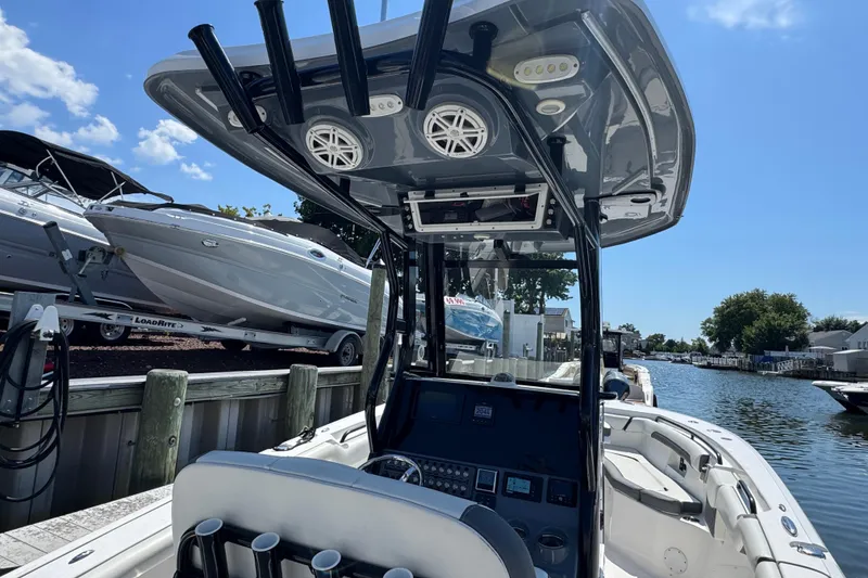 Slide: The Image of 2021 Tidewater 272 CC Adventure boat interior with console and seating, docked by a canal. - 6