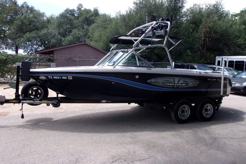 Slide: The Image of 2005 Correct Craft 210 Super Air Team Edition boat on trailer, parked outdoors. - 1