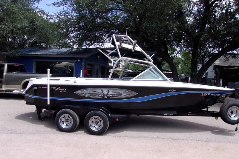 Slide: The Image of 2005 Correct Craft 210 Super Air Team Edition boat on trailer, parked outdoors. - 2