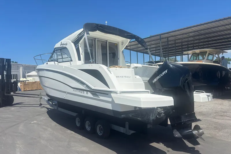 Slide: The Image of 2021 Beneteau Antares 8 boat with Mercury engine on trailer, parked outdoors. - 2