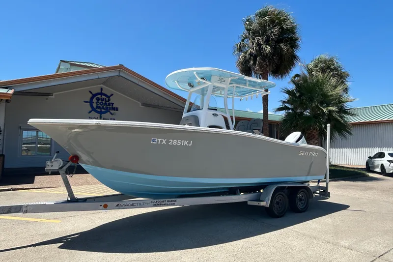 Slide: The Image of 2021 Sea Pro 239 Center Console boat on trailer, parked outdoors under clear sky. - 2