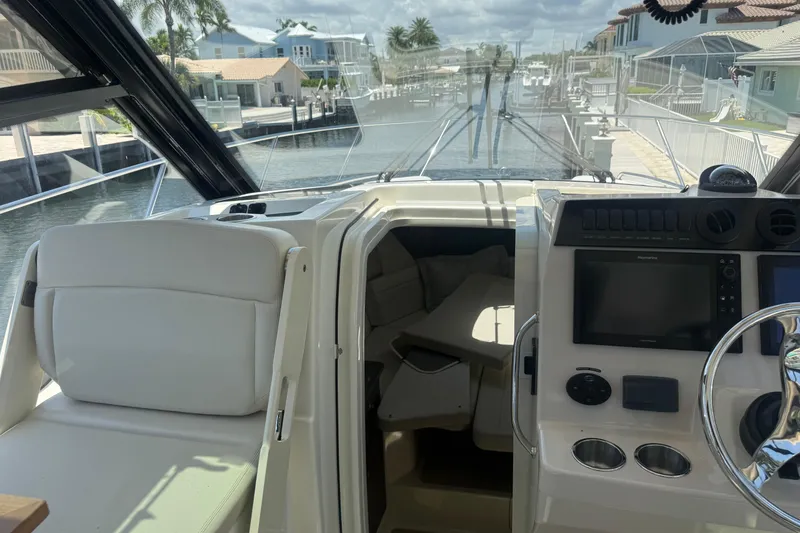 Slide: The Image of 2021 Boston Whaler 325 Conquest cockpit with helm, seating, and canal view. - 9