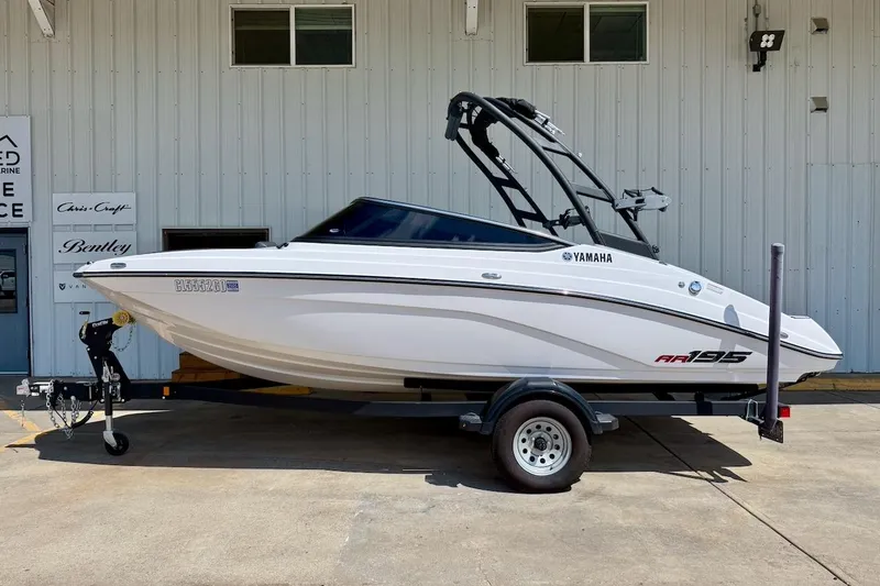 Slide: The Image of 2025 Yamaha Boats AR195 on trailer, parked outside a marine service building. - 1