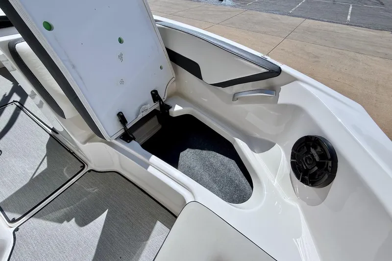 Slide: The Image of 2025 Yamaha AR195 boat interior storage compartment with open seat and speaker. - 16