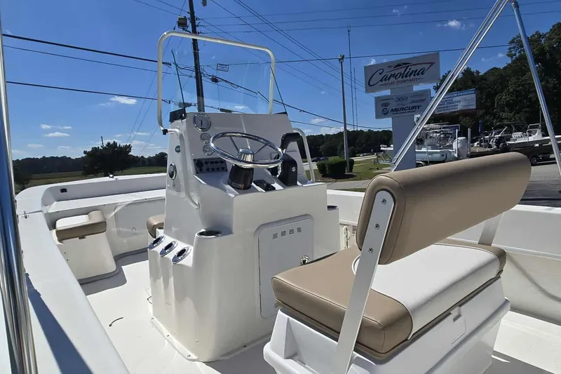 Slide: The Image of 2026 Sundance B20CCR boat interior with steering console and seating, under clear blue sky. - 4