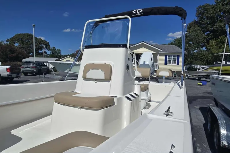 Slide: The Image of 2026 Sundance B20CCR boat with beige seating, parked outdoors under a clear blue sky. - 6