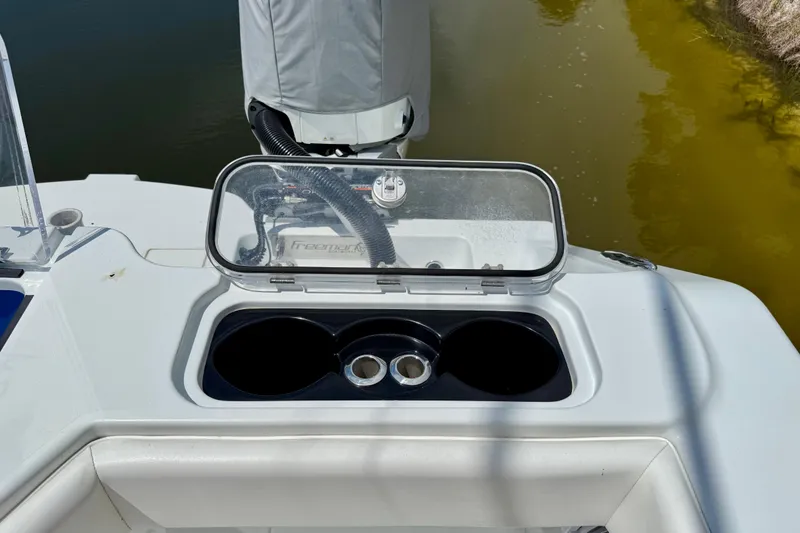 Slide: The Image of Open storage compartment on 2023 Freeman 34VH boat, featuring cup holders and engine access. - 11