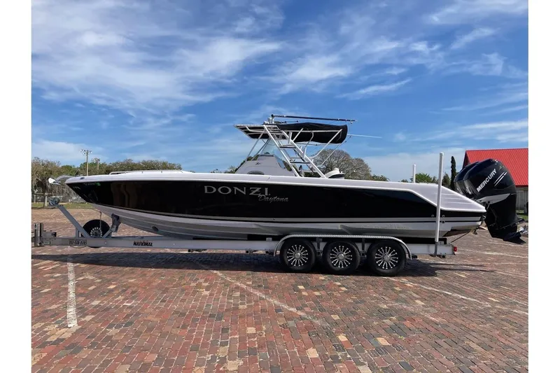 The Image of 2005 Donzi 35 ZF Daytona boat on trailer, parked on brick pavement under blue sky. - 1