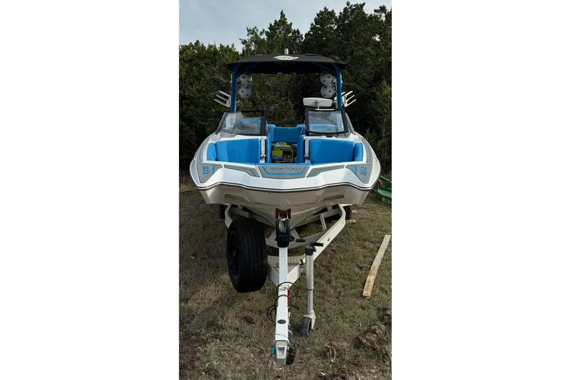 Slide: The Image of 2022 Malibu Wakesetter 23 MXZ boat on trailer, blue interior, parked on grass. - 6