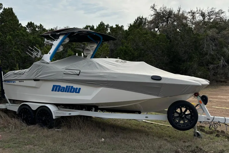 Slide: The Image of 2022 Malibu Wakesetter 23 MXZ boat covered on trailer, surrounded by trees. - 7