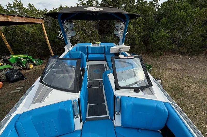 Slide: The Image of 2022 Malibu Wakesetter 23 MXZ boat with blue seating and sleek design in a wooded area. - 8