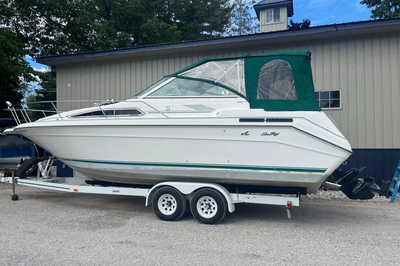 The Image of 1991 Sea Ray 270 Sundancer boat on trailer, parked near a building. - 1