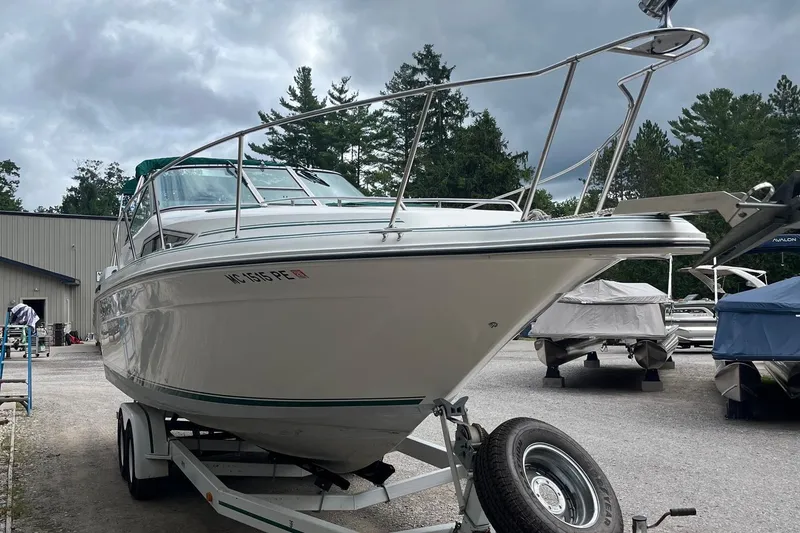 Slide: The Image of 1991 Sea Ray 270 Sundancer boat on trailer, parked outdoors under cloudy sky. - 20
