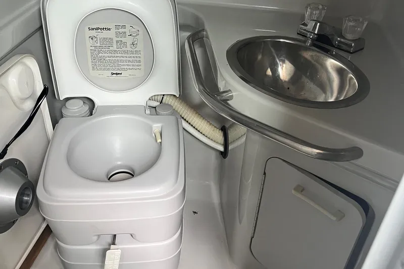 Slide: The Image of 1991 Sea Ray 270 Sundancer bathroom with portable toilet and stainless steel sink. - 6
