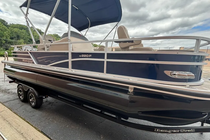 Slide: The Image of 2025 Ranger 220F pontoon boat with blue exterior and canopy on a trailer. - 11