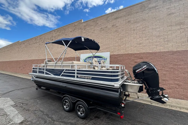 Slide: The Image of 2025 Ranger 220F pontoon boat with Mercury outboard motor, parked outdoors. - 2