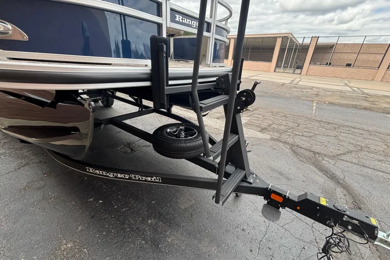 Slide: The Image of 2025 Ranger 220F boat trailer with steps and spare tire on asphalt. - 4
