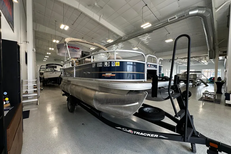 Slide: The Image of 2023 Sun Tracker Bass Buggy 16 XL Select pontoon boat in showroom on trailer. - 2