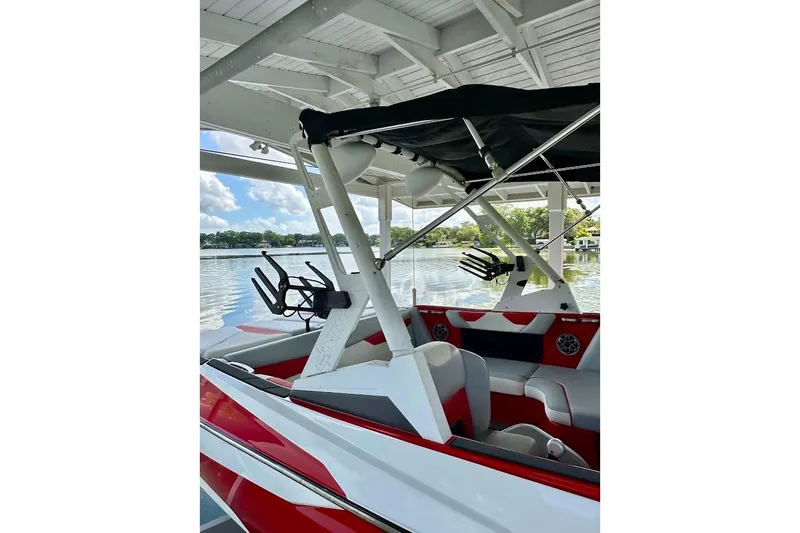 Slide: The Image of 2021 Axis A20 boat with red and white interior, docked under a canopy by a lake. - 44