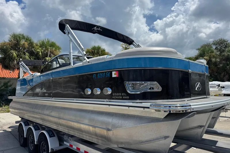Slide: The Image of 2019 Avalon Catalina Platinum Elite pontoon boat on trailer, under cloudy sky. - 3