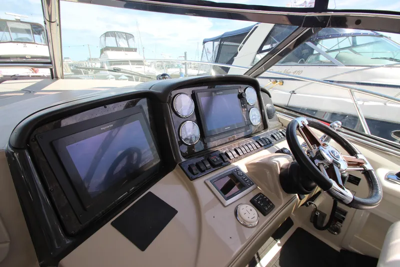 Slide: The Image of 2008 Sea Ray 44 Sundancer helm with navigation screens and steering wheel in marina setting. - 17