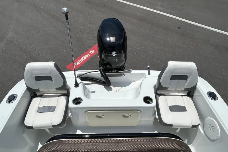 Slide: The Image of 2020 Key Largo 1800 CC boat interior with seating and motor, parked on asphalt. - 13