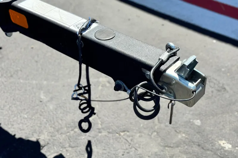 Slide: The Image of Trailer hitch of a 2021 Tahoe T700 on asphalt, featuring safety chains and coupler. - 26