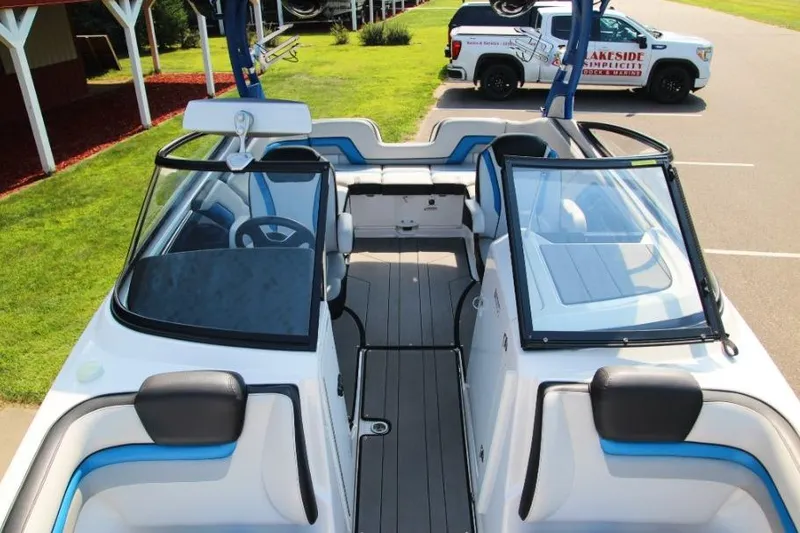 Slide: The Image of 2019 Yamaha Boats 242X interior with seating and steering wheel, parked near a truck. - 7
