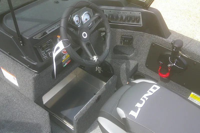 Slide: The Image of 2026 Lund 1875 Impact XS Sport boat interior with steering wheel and dashboard controls. - 14