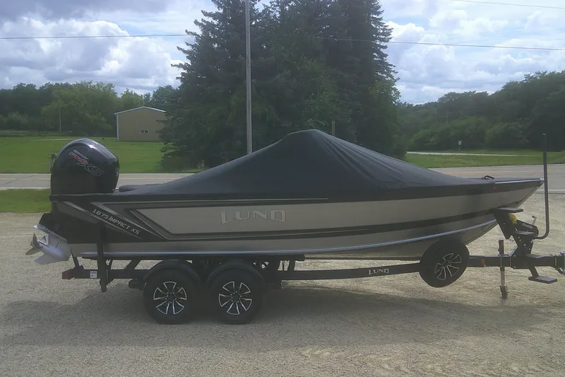 Slide: The Image of 2026 Lund 1875 Impact XS Sport boat on trailer, covered, outdoors. - 19