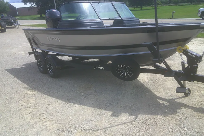 Slide: The Image of 2026 Lund 1875 Impact XS Sport boat on trailer, parked outdoors. - 2