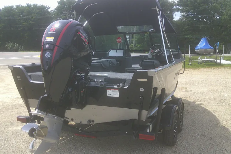 Slide: The Image of 2026 Lund 1875 Impact XS Sport boat with powerful outboard motor, parked on a trailer. - 4