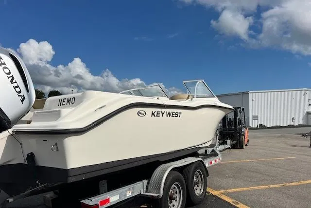 Slide: The Image of 2019 Key West 239 DFS boat on trailer, parked outdoors under blue sky. - 1