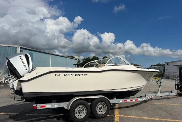 Slide: The Image of 2019 Key West 239 DFS boat on trailer, parked outdoors under a cloudy sky. - 2