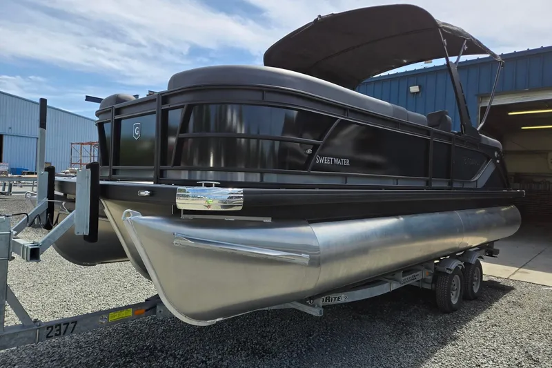 Slide: The Image of 2026 Godfrey SWEETWATER 2286 SB pontoon boat on trailer, parked outside a blue building. - 4
